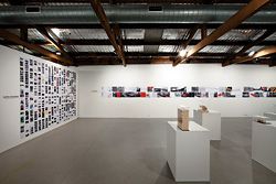 Installation view, with Marcus Trimble’s blog Super Colossal on the left. The back wall shows Choi Ropiha’s Ballast Point Park, Sydney, and the TKTS booth in New York. Photography Murray Fredericks, courtesy of Boutwell Draper Gallery, Sydney.