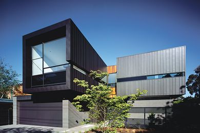 The building form contrasts solid mass with walls of glass.