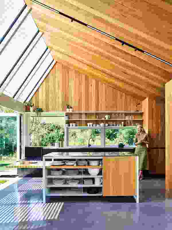 Blackbutt, lining the kitchen’s walls and one side of its raked ceiling, gives way to glazing that allows sunlight to flood inside.