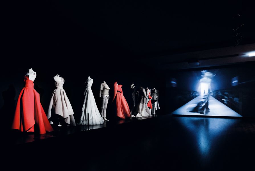 Theatrical lighting shines down on the gowns, making them pop in the dark space.